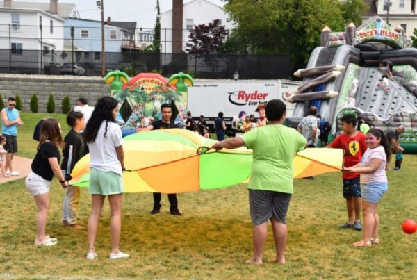 Youth playing with a tent outside, bouncy houses in the background.