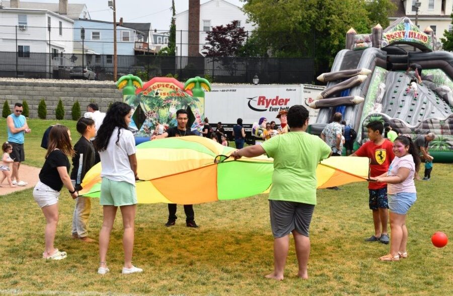 Youth playing with a tent outside, bouncy houses in the background.