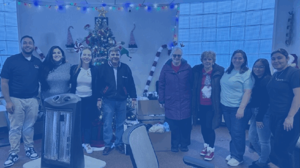 People standing in a row next to a box of donated items.