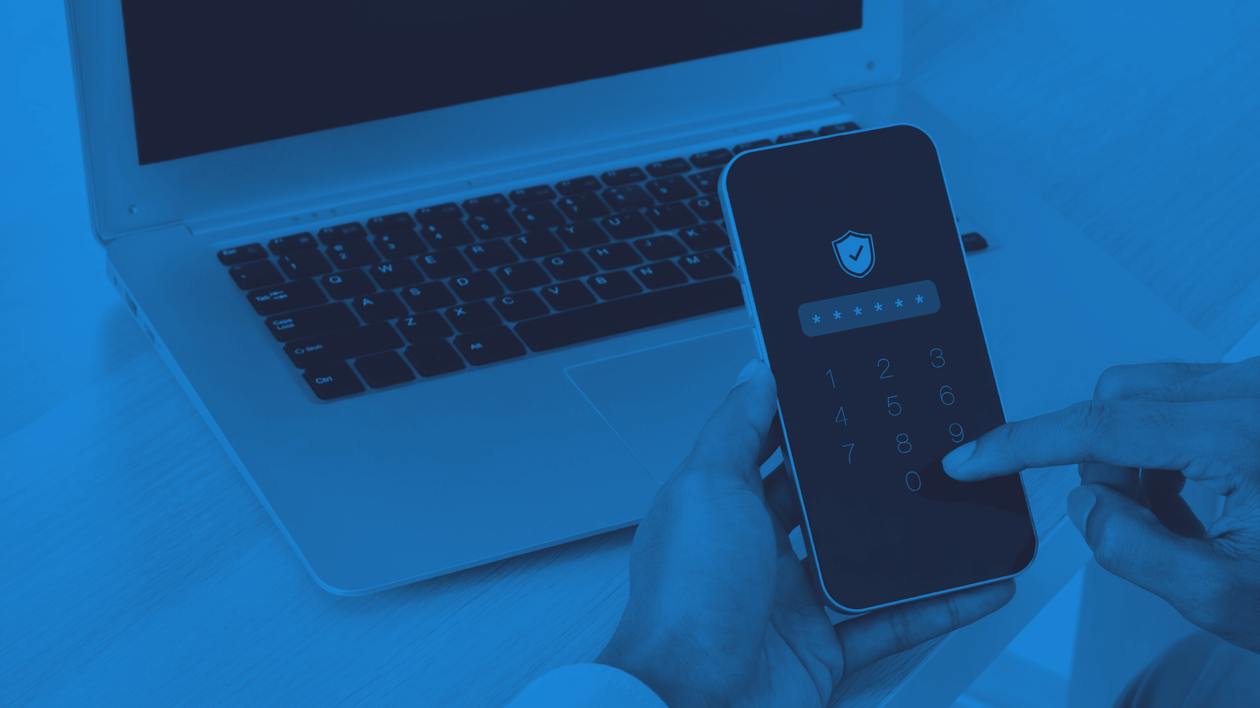 A person changing their password on their phone in front of a laptop