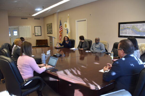 Rev. Dr. Myrlande DesRosiers speaks to a group of Councilors, Mayor, and community leaders at table.