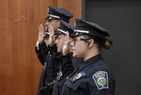 Everett police officers standing in a row with their hands raised as they take the pledge.