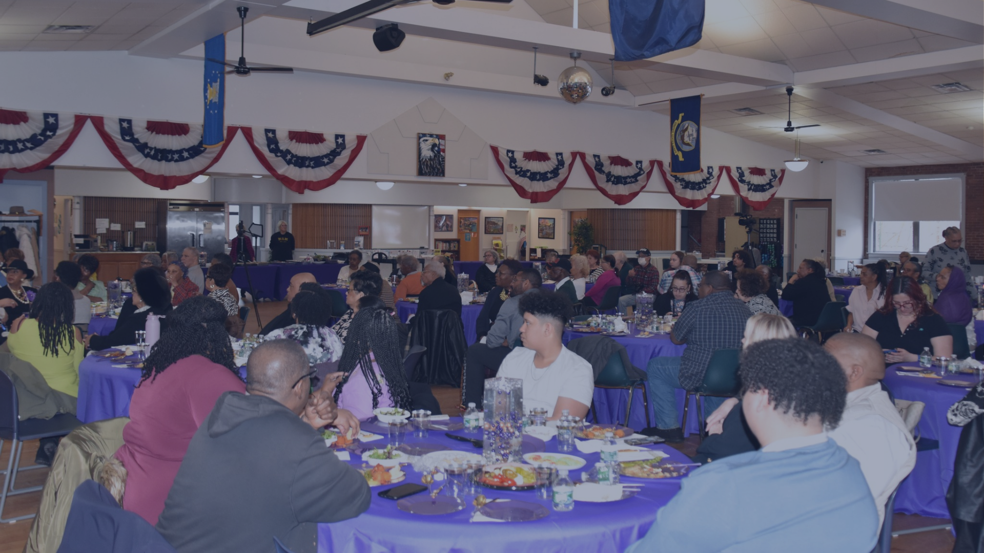 Community members sit at round tables with purple tablecloths during a last year's Women's History Month luncheon inside the Connolly Center.