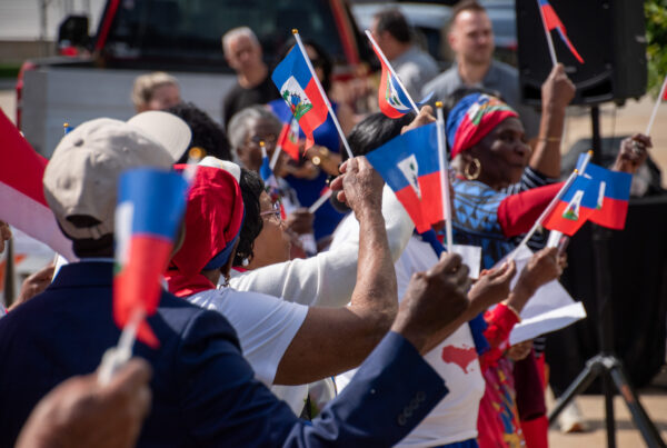 People cheering and raising their Haitian flags in a sea of blue, white, and red.