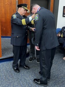 Chief Strong putting the medal of valor around Det Wall's neck 