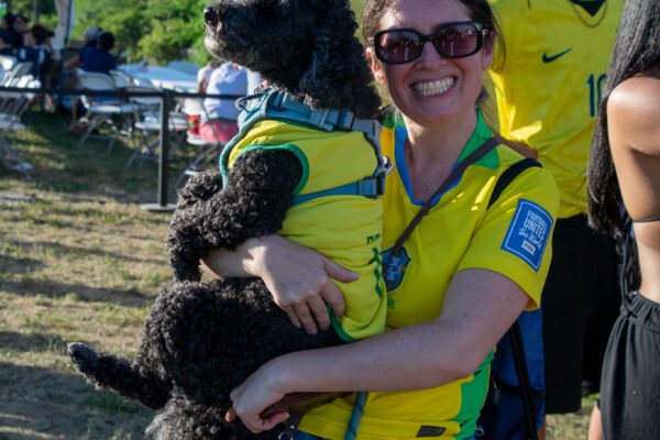 Brazil fan poses with her dog, who is also wearing a Brazil jersey.