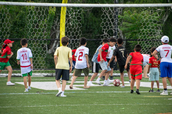 Youth playing soccer just steps from the professional athletes on the screen at Fan Fest.