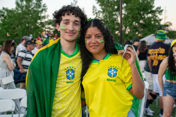 Brazil fans hugging beneath a Brazil flag.