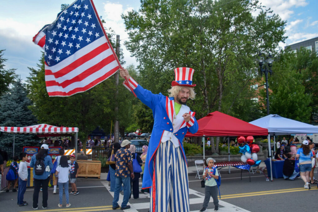 A stilt performer dressed as Uncle Sam points smiling at the camera.
