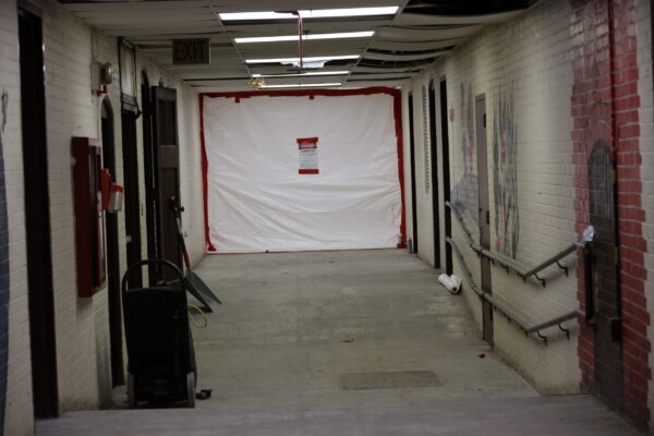 An empty hallway with a tarp covering the end of it where remediation work is happening