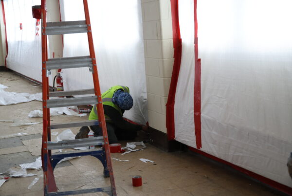 worker kneeling on the floor as they remediate the floors and walls