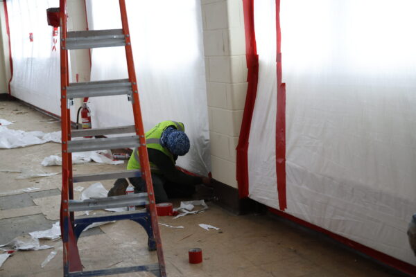 worker kneeling on the floor as they remediate the floors and walls
