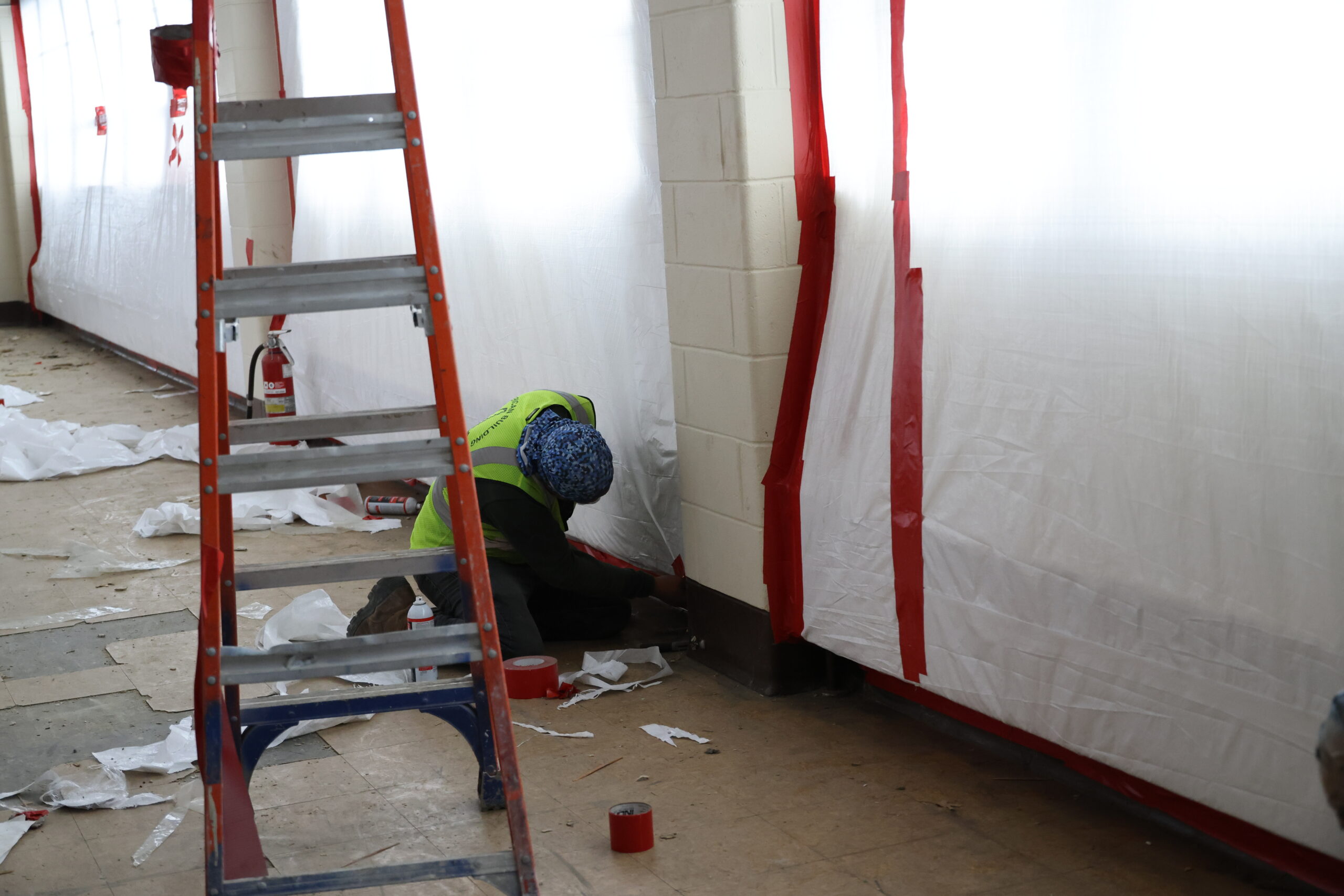 worker kneeling on the floor as they remediate the floors and walls