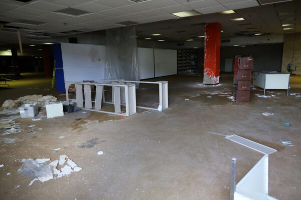 A ladder is laying sideways on the floor, towels and other materials on thrown about in an empty room that once was a library