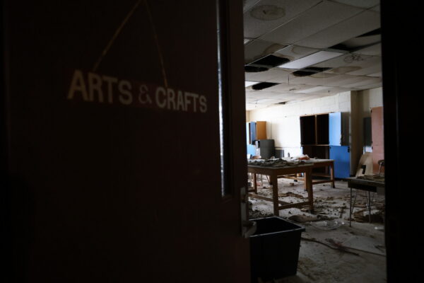 A half-open door that reads "arts and crafts" showing a classroom in disarray