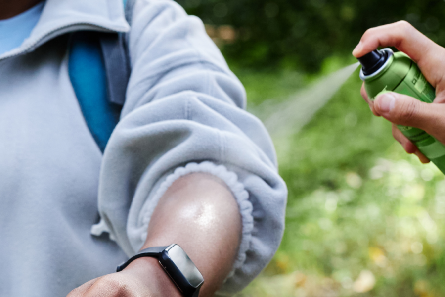 Person sprays insect repellent on another person.